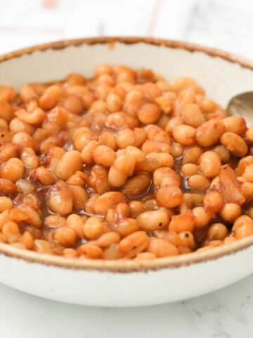 Homemade Baked Beans in white bowl with spoon.