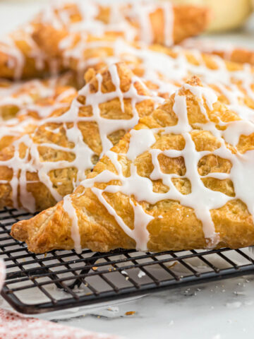 air fryer pumpkin turnovers on cooling rack drizzled with glaze.